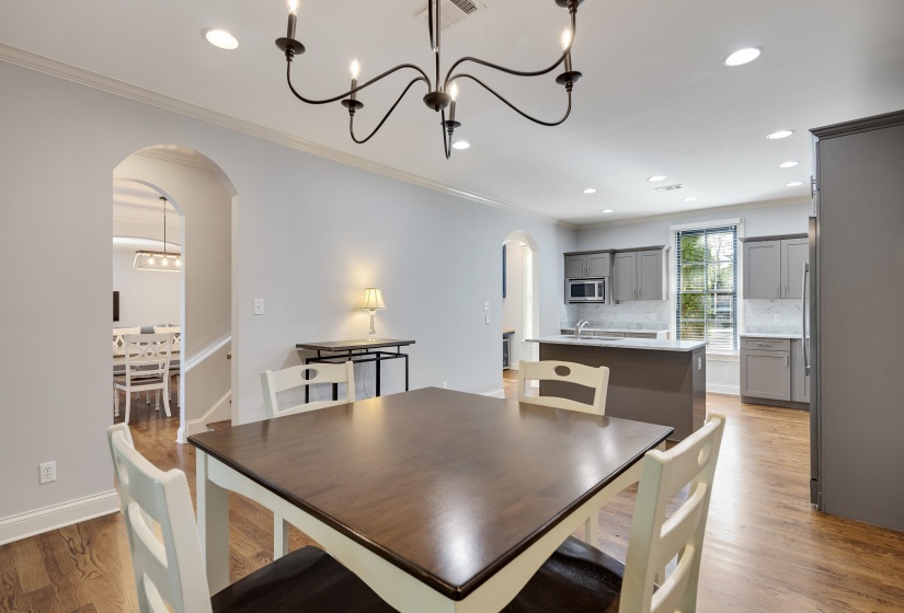 Dining area featuring arched walkways, crown molding, light wood-style flooring, and hanging lights
