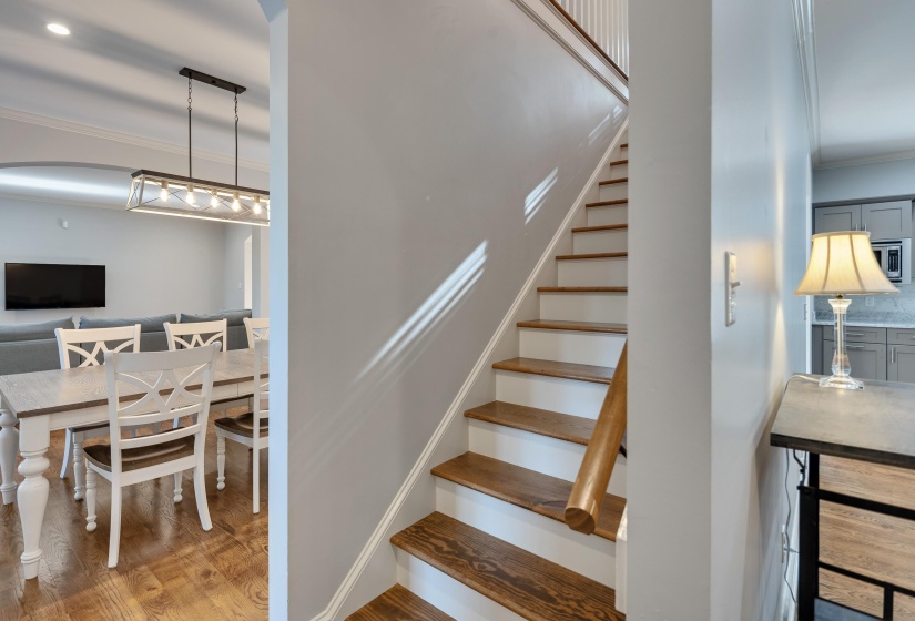 Stairs featuring ornamental molding, wood finished floors, and arched walkways
