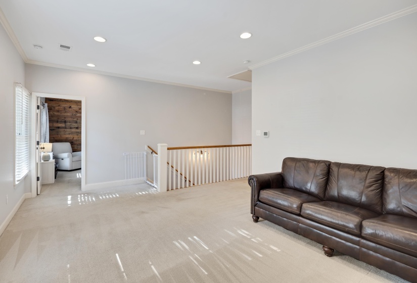 Living room with ornamental molding, recessed lighting, and light carpet