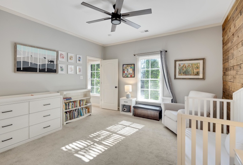 Bedroom with crown molding, a crib, light carpet, and a ceiling fan