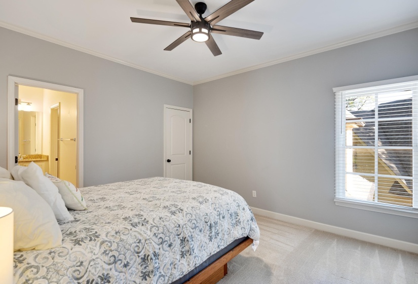 Bedroom with ornamental molding, light colored carpet, a ceiling fan, and connected bathroom