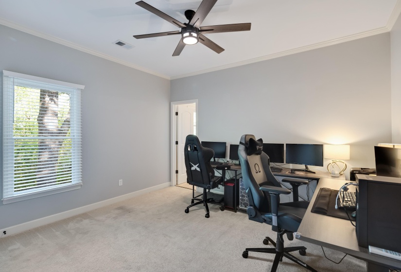 Office space with ornamental molding, light carpet, and a ceiling fan