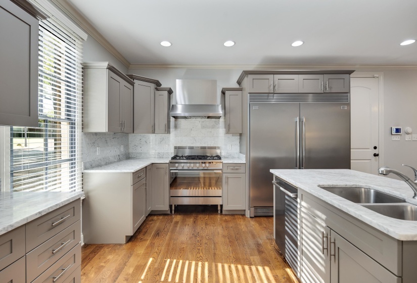 Kitchen featuring gray cabinetry, ornamental molding, light stone counters, stainless steel appliances, and backsplash
