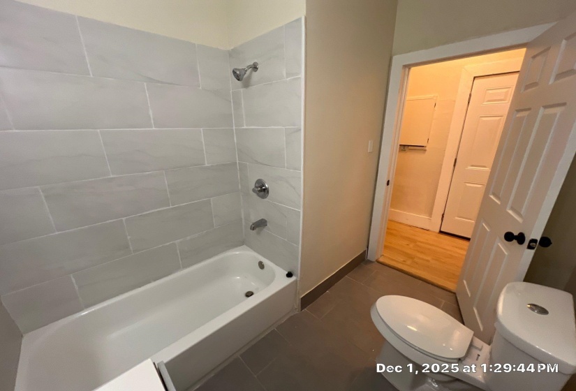 Bathroom featuring bathtub / shower combination and dark tile patterned flooring