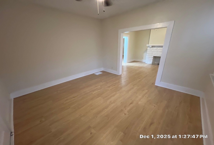 Unfurnished room with light wood finished floors, a brick fireplace, and a ceiling fan