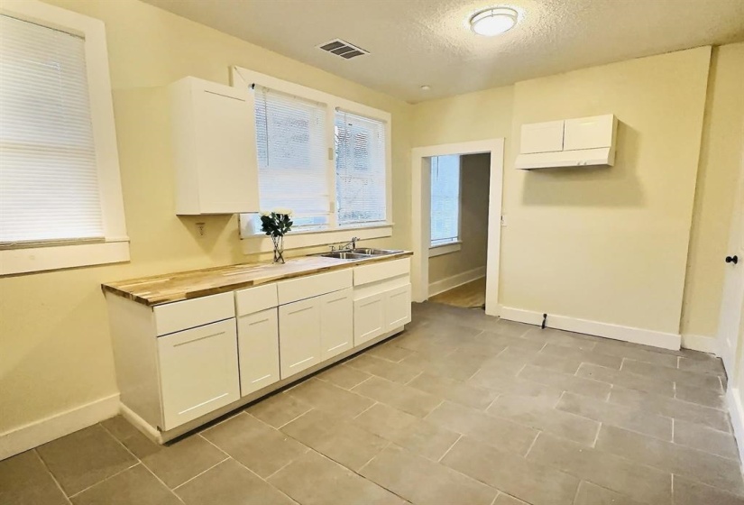 Kitchen featuring white cabinets, a textured ceiling, and wooden counters