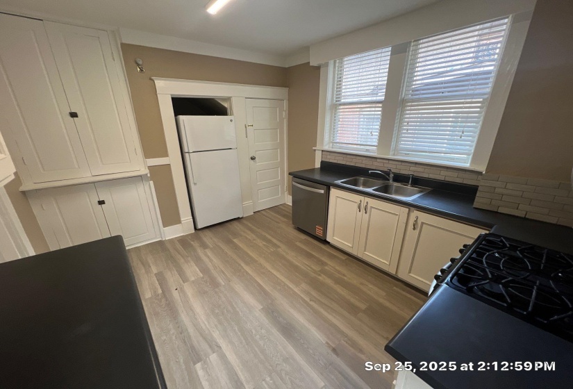 Kitchen featuring dark countertops, freestanding refrigerator, white cabinetry, gas stove, and dishwasher
