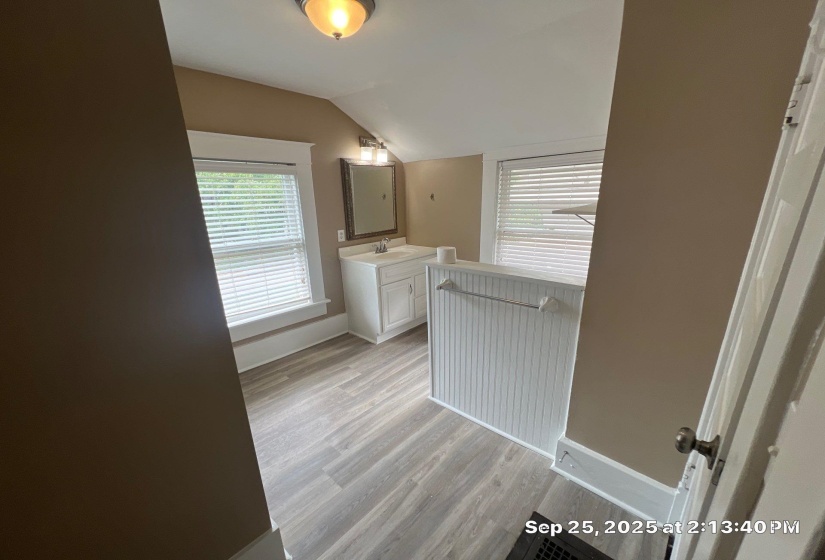 Bathroom with vaulted ceiling, vanity, and light wood-style floors