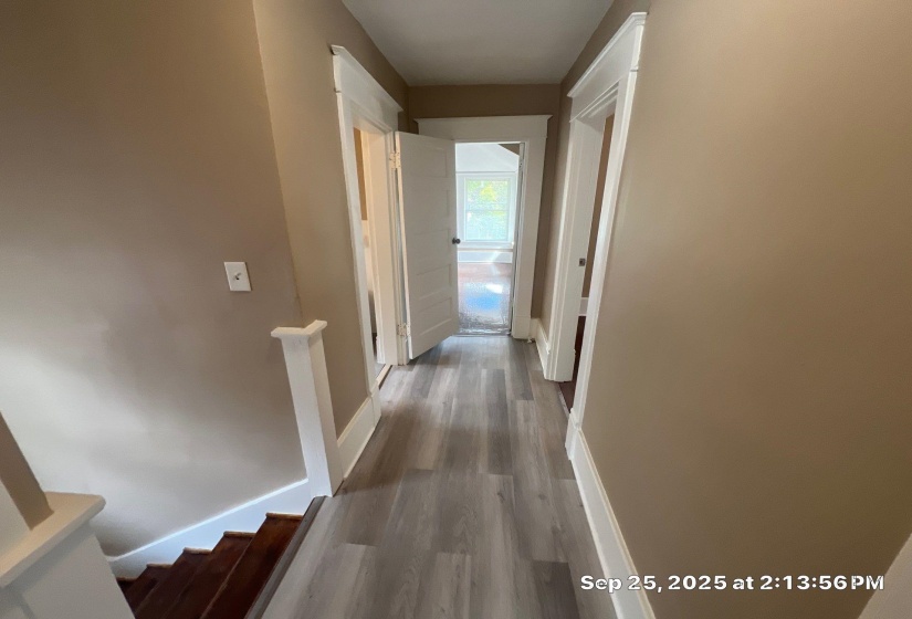 Hall with dark wood-style flooring and baseboards