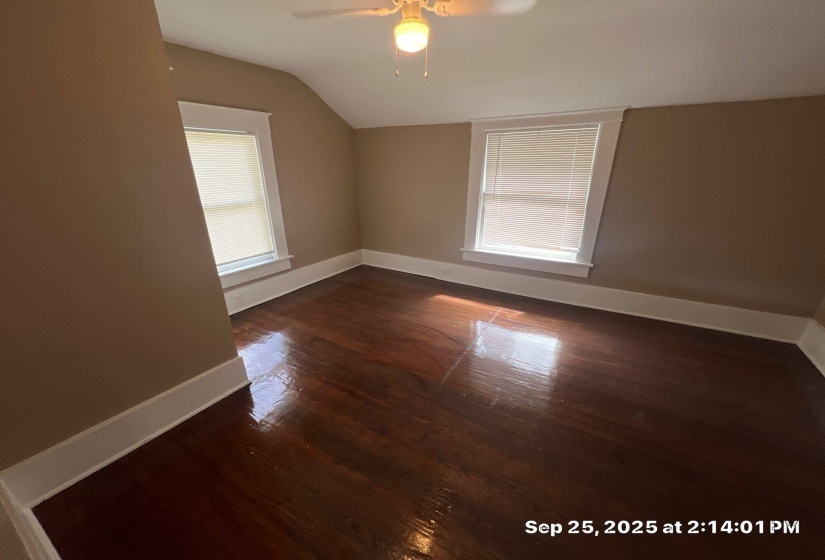 Additional living space featuring dark wood finished floors, vaulted ceiling, and a ceiling fan