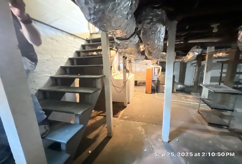 Unfinished below grade area with stairway and brick wall