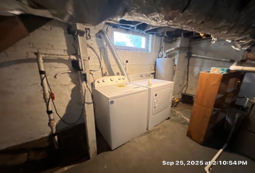 Laundry area with water heater, unfinished concrete floors, and washing machine and clothes dryer