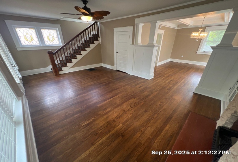 Unfurnished living room with dark wood-style floors, ceiling fan, hanging lights, and ornamental molding