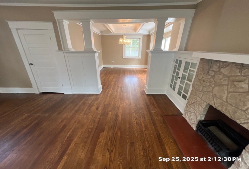 Unfurnished living room with ornamental molding, dark wood-style flooring, a fireplace, and a chandelier