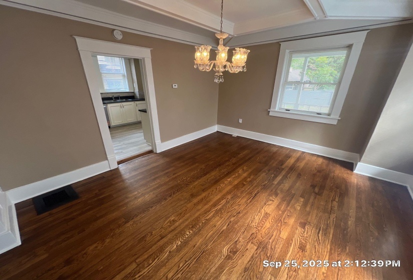Unfurnished dining area with dark wood-type flooring, hanging lights, and crown molding