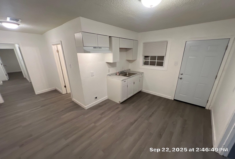 Kitchen with light countertops, a textured ceiling, dark wood-style flooring, and white cabinets