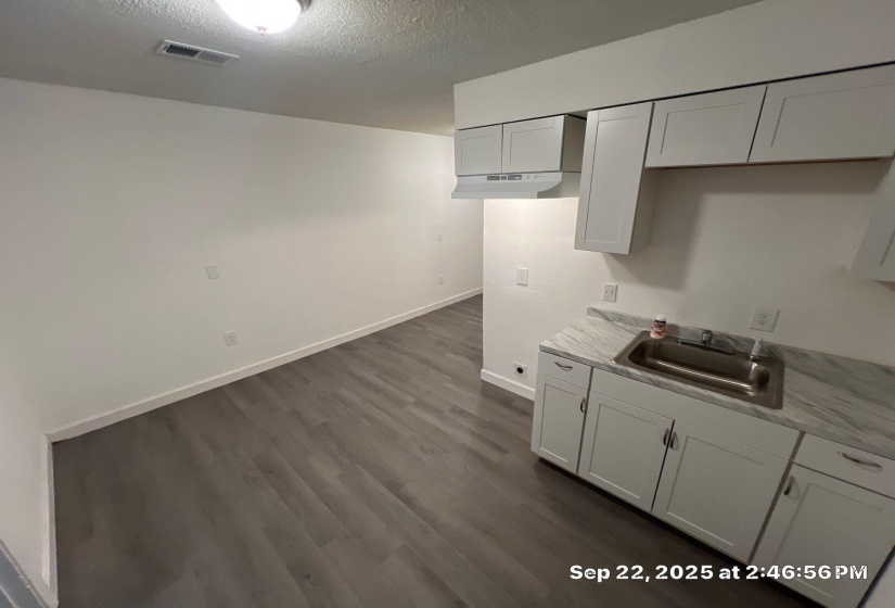 Kitchen featuring light countertops, a textured ceiling, dark wood-style flooring, and white cabinets