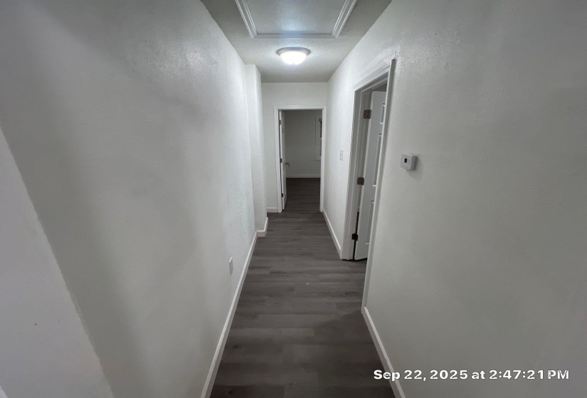 Hall featuring dark wood-style floors and a textured wall