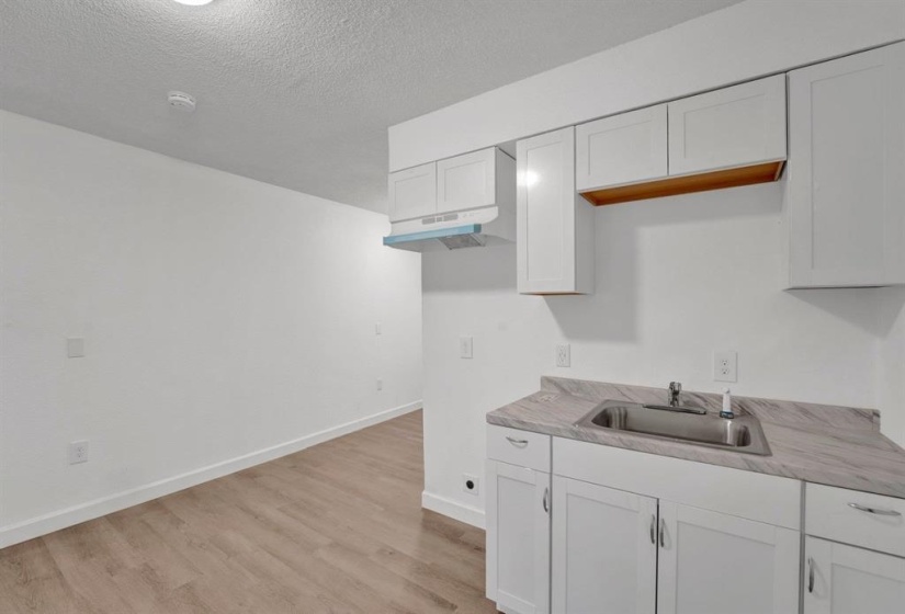 Kitchen featuring light countertops, light wood-style flooring, white cabinetry, and a textured ceiling