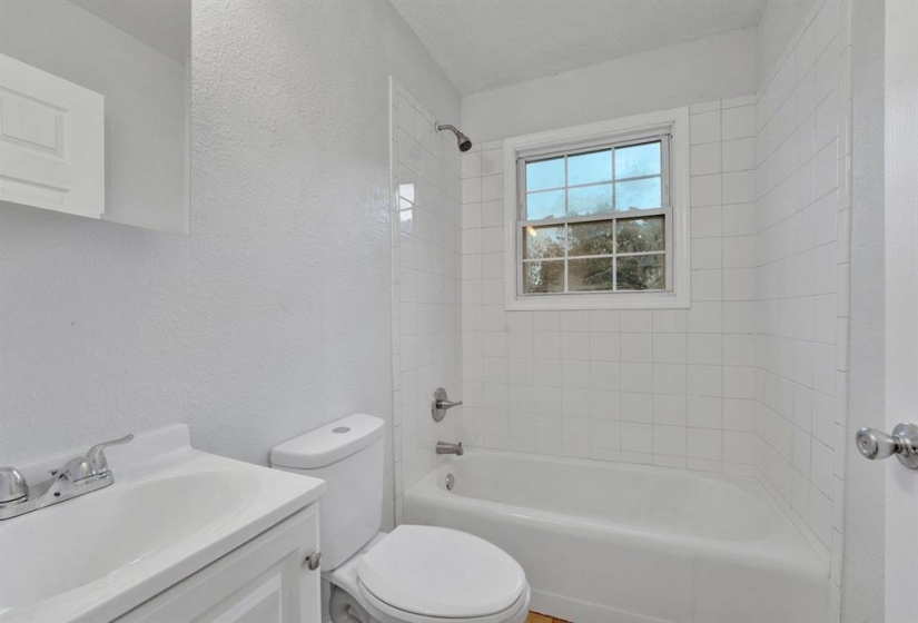Full bathroom with a textured wall, vanity, and bathtub / shower combination