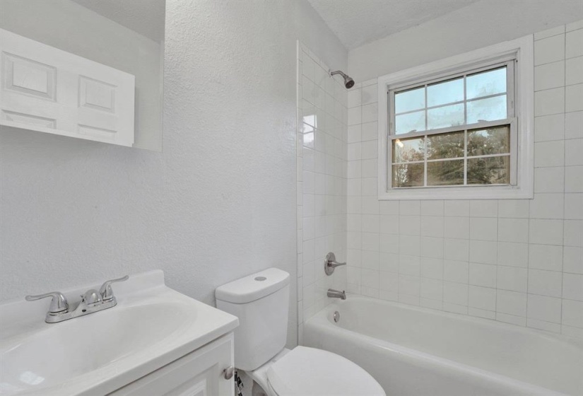 Full bath with a textured wall, vanity, and shower / bath combination