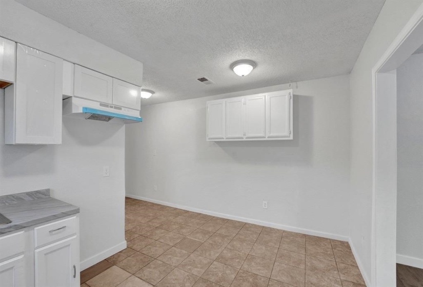 Kitchen with a textured ceiling, light countertops, and white cabinets
