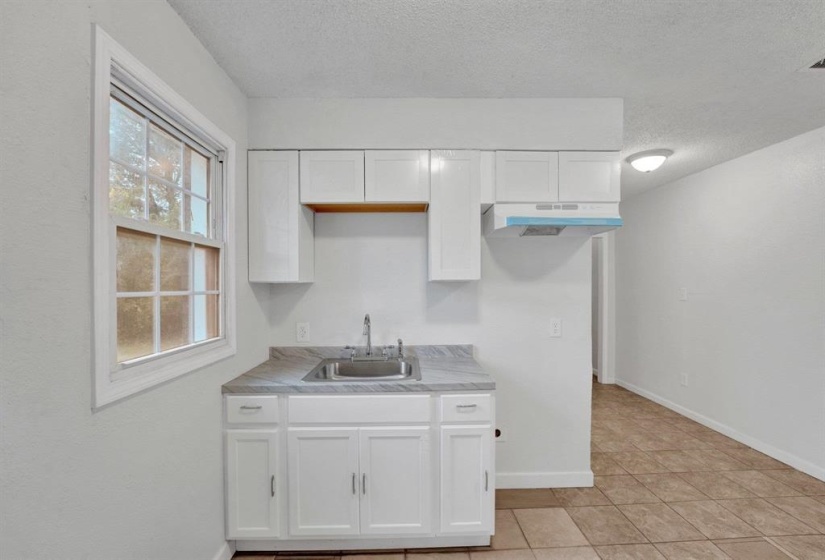 Kitchen featuring white cabinets, a textured ceiling, light countertops, and light tile patterned floors