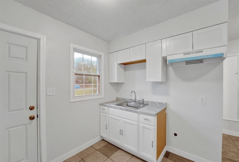Kitchen with light countertops, white cabinets, a textured ceiling, and light tile patterned flooring
