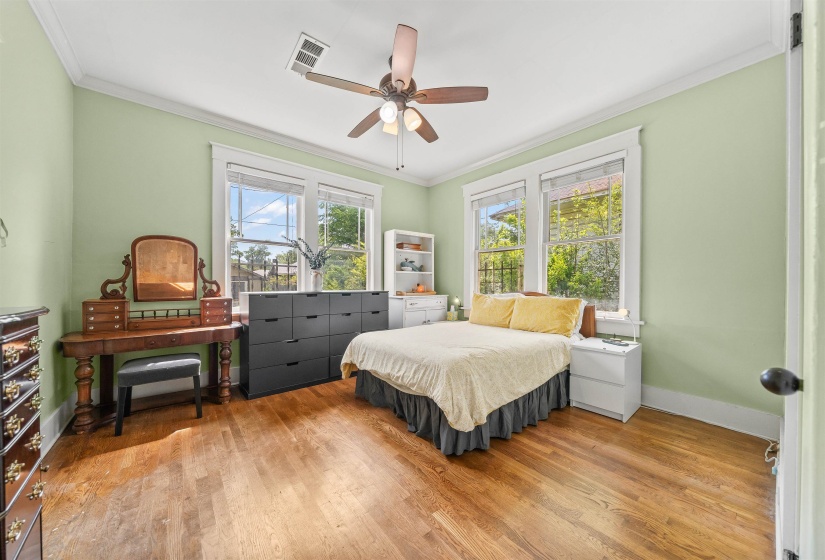 Bedroom with crown molding, light wood-style floors, and a ceiling fan