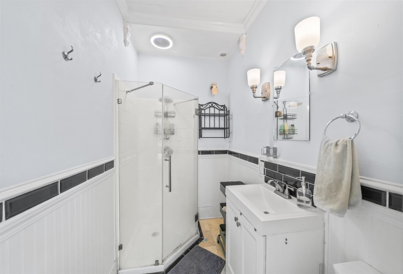 Bathroom with vanity, a shower stall, and wainscoting