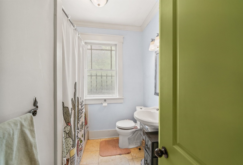 Bathroom with ornamental molding, a shower with shower curtain, and light tile patterned floors