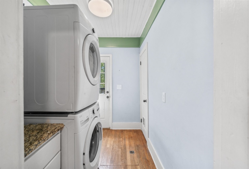 Laundry area featuring light wood-type flooring and stacked washer and dryer