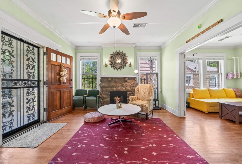 Living area with ornamental molding, wood finished floors, a fireplace, and a ceiling fan