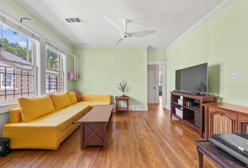 Living room with crown molding, wood finished floors, and ceiling fan