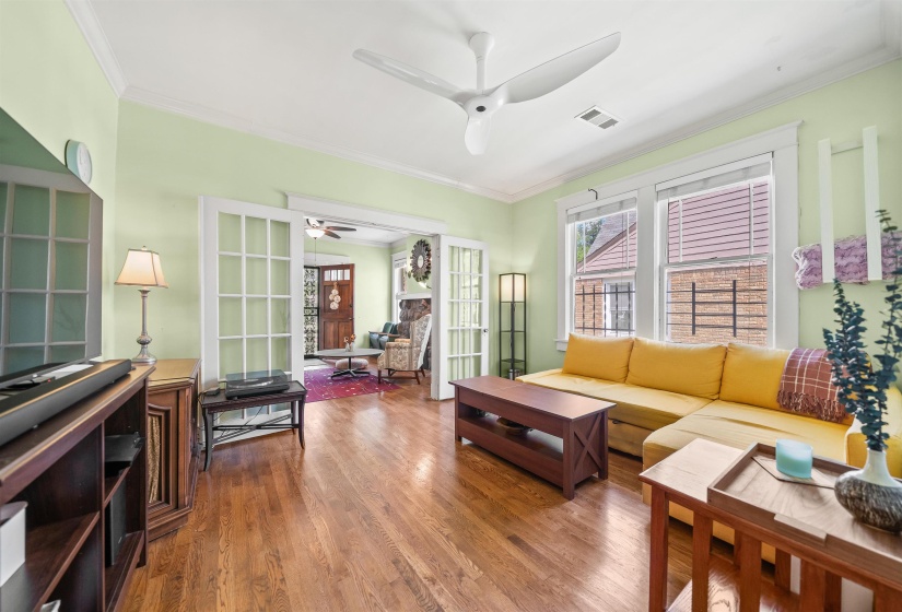 Living area featuring crown molding, wood finished floors, ceiling fan, and french doors