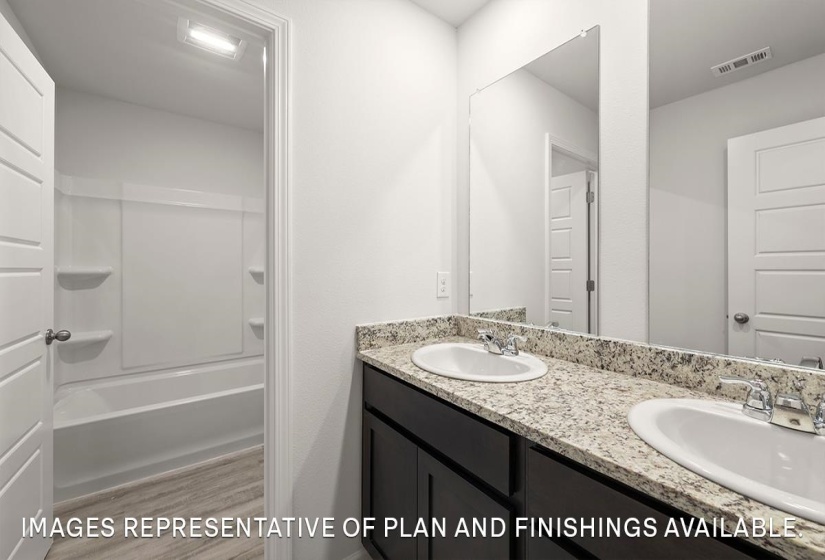 Full bathroom with double vanity, light wood-type flooring, and bathtub / shower combination
