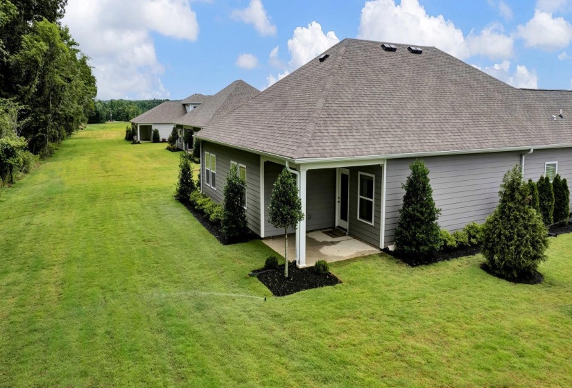Rear view of property with a lawn, a patio area, and a shingled roof