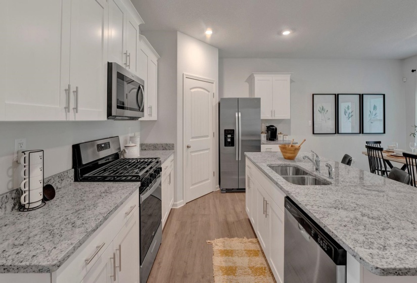 Kitchen with stainless steel appliances, white cabinetry, an island with sink, and recessed lighting