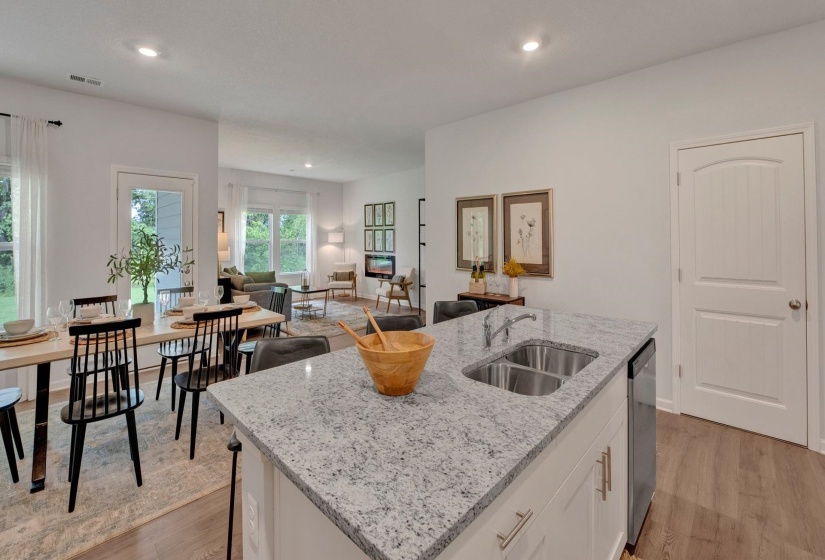 Kitchen with white cabinets, light stone countertops, light wood-style floors, recessed lighting, and an island with sink