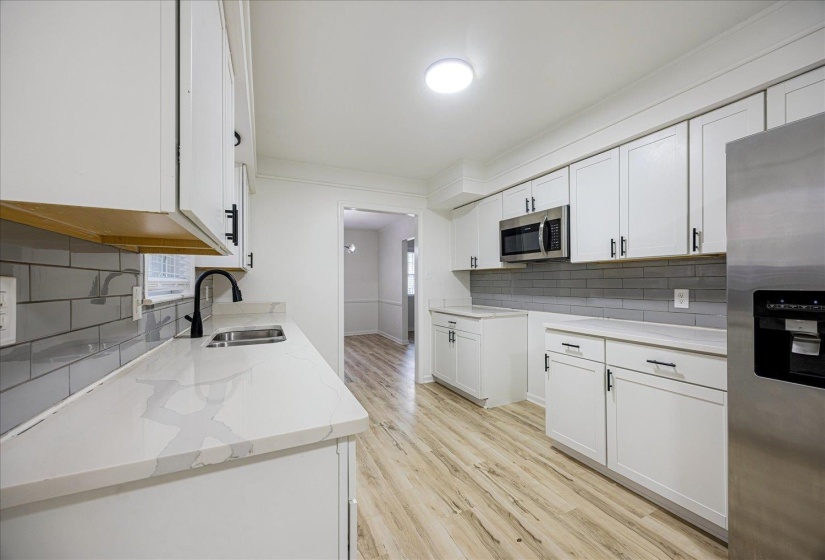 Kitchen featuring light wood-style flooring, white cabinets, stainless steel appliances, and crown molding