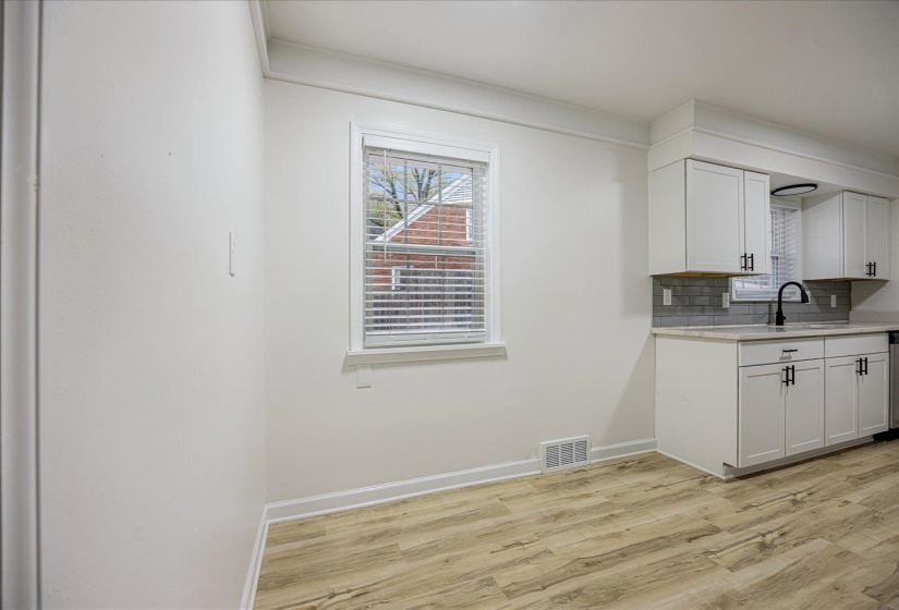 Kitchen with white cabinetry, light wood-type flooring, and decorative backsplash