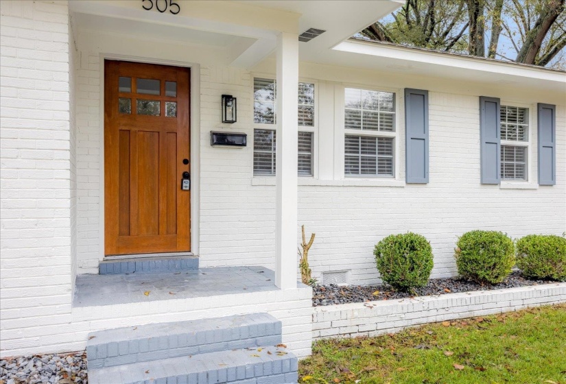 Entrance to property featuring covered porch and brick siding
