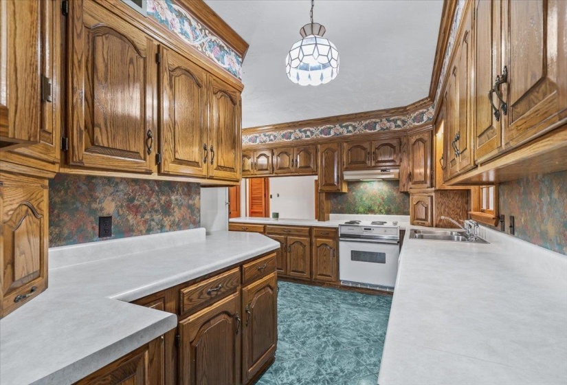 Kitchen with light countertops, white range with electric cooktop, ornamental molding, tasteful backsplash, and brown cabinets