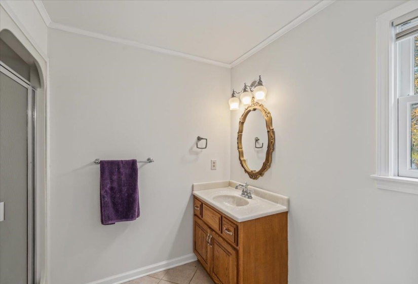 Full bath with vanity, ornamental molding, light tile patterned floors, and a stall shower