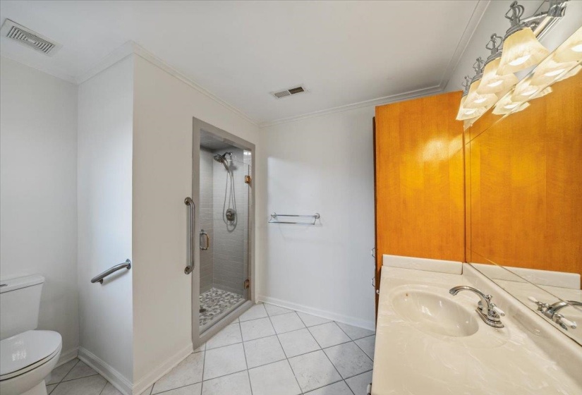 Bathroom featuring crown molding, light tile patterned floors, vanity, and a shower stall