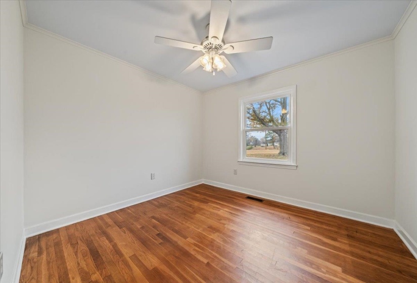 Spare room with crown molding, wood finished floors, and a ceiling fan