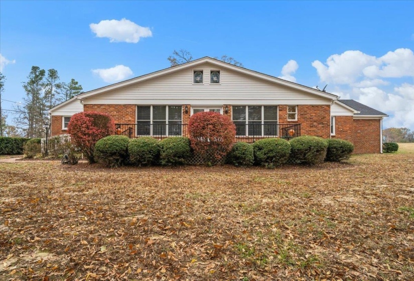Back of house featuring brick siding and a yard