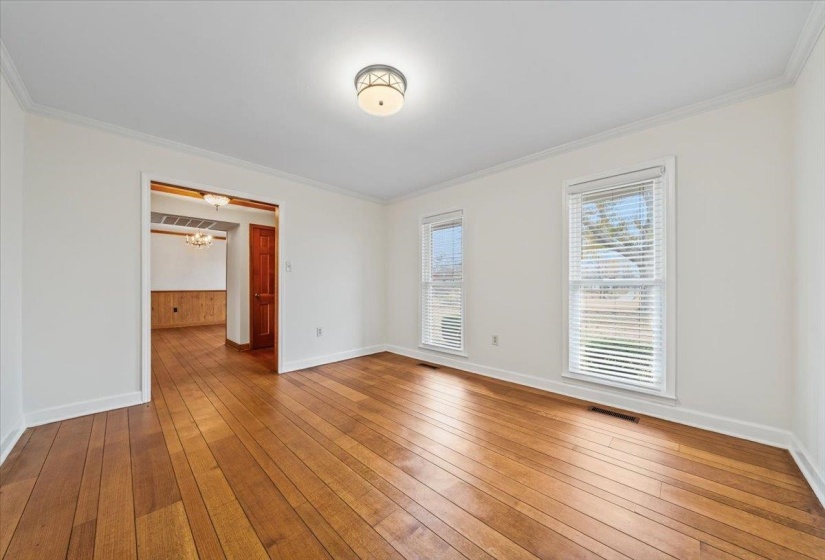 Unfurnished room featuring crown molding, hardwood / wood-style floors, and a chandelier