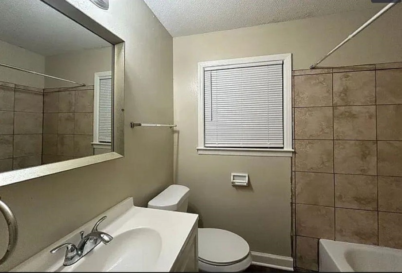 Full bath with a textured ceiling, vanity, and  shower combination