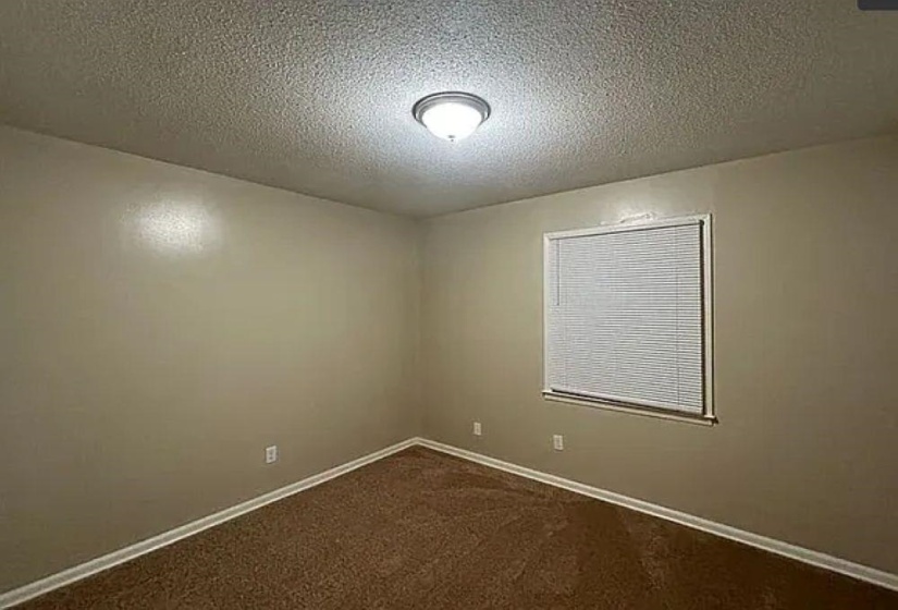 Unfurnished room featuring a textured ceiling and dark carpet